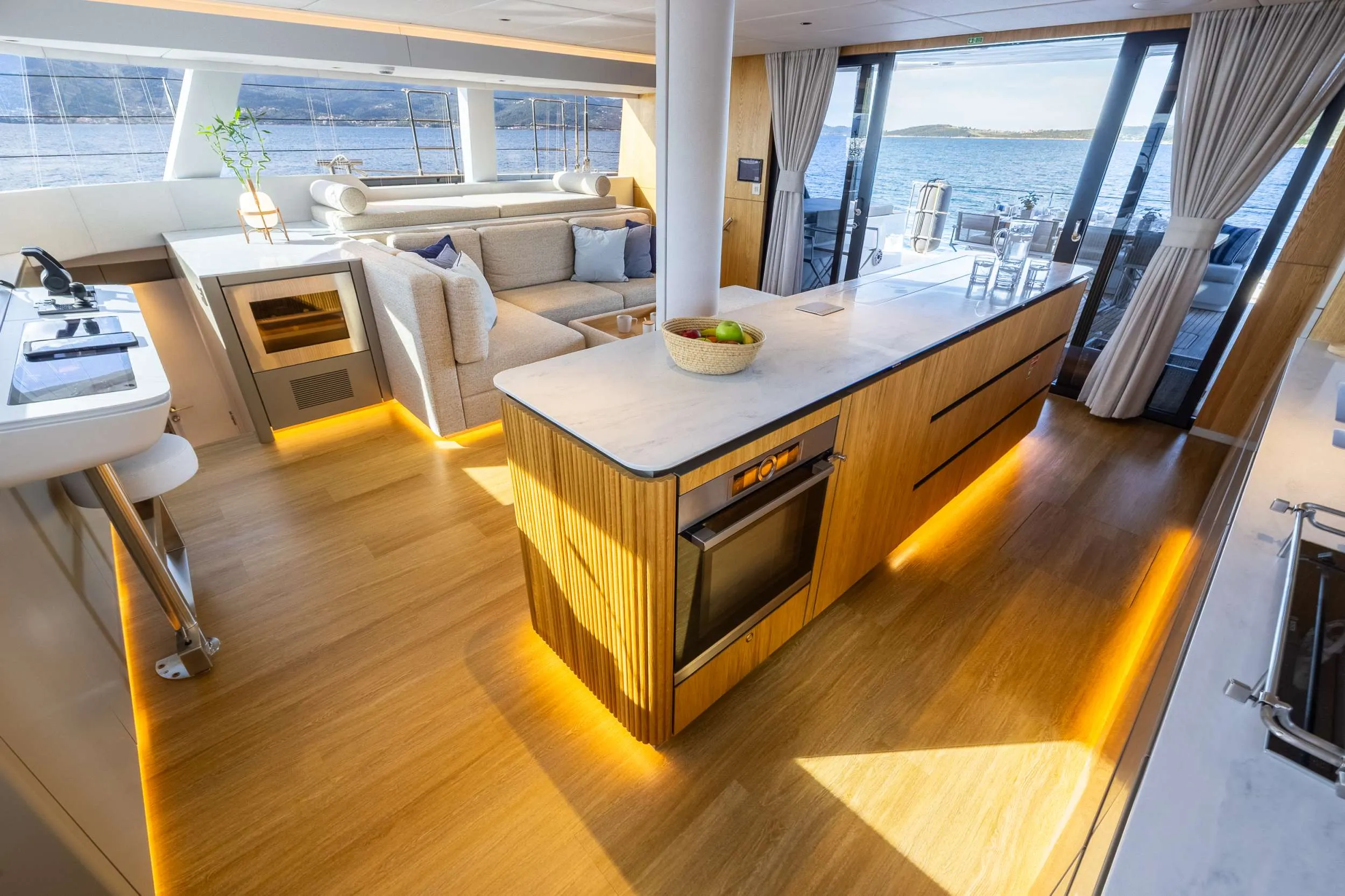 The galley, where the APA turns into lunch The galley and saloon of a crewed catamaran, with the chef’s counter and a view to the sea