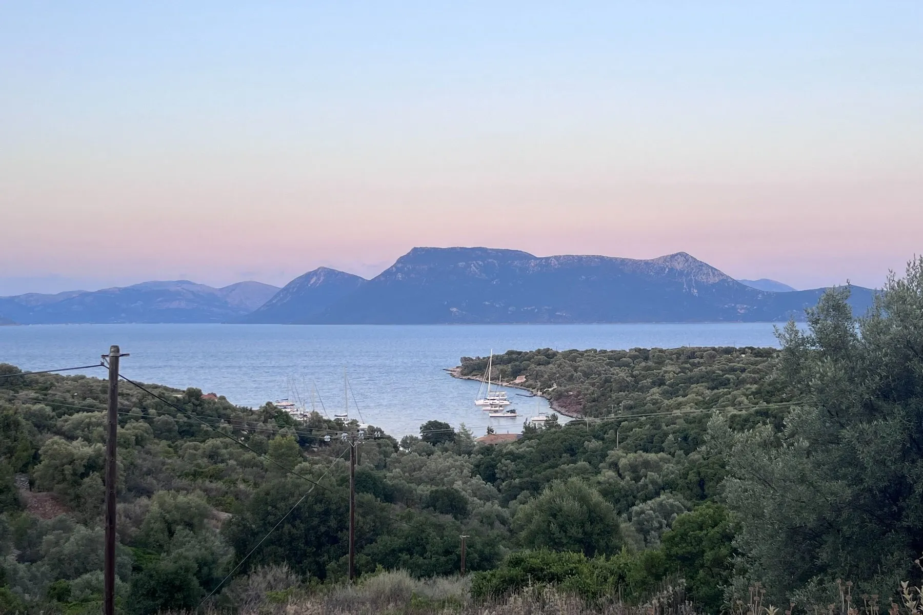 Meganisi at dusk - Oasis Sailing Dusk over a Meganisi anchorage, two yachts on the water with the mountains behind
