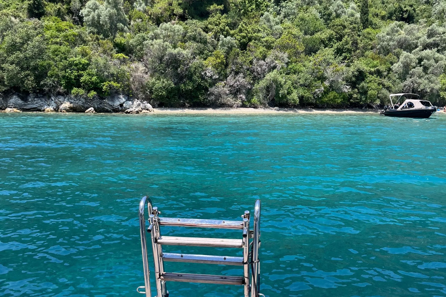 Morning swim - Oasis Sailing A swim ladder lowered into clear green water off the stern, early, in a quiet bay