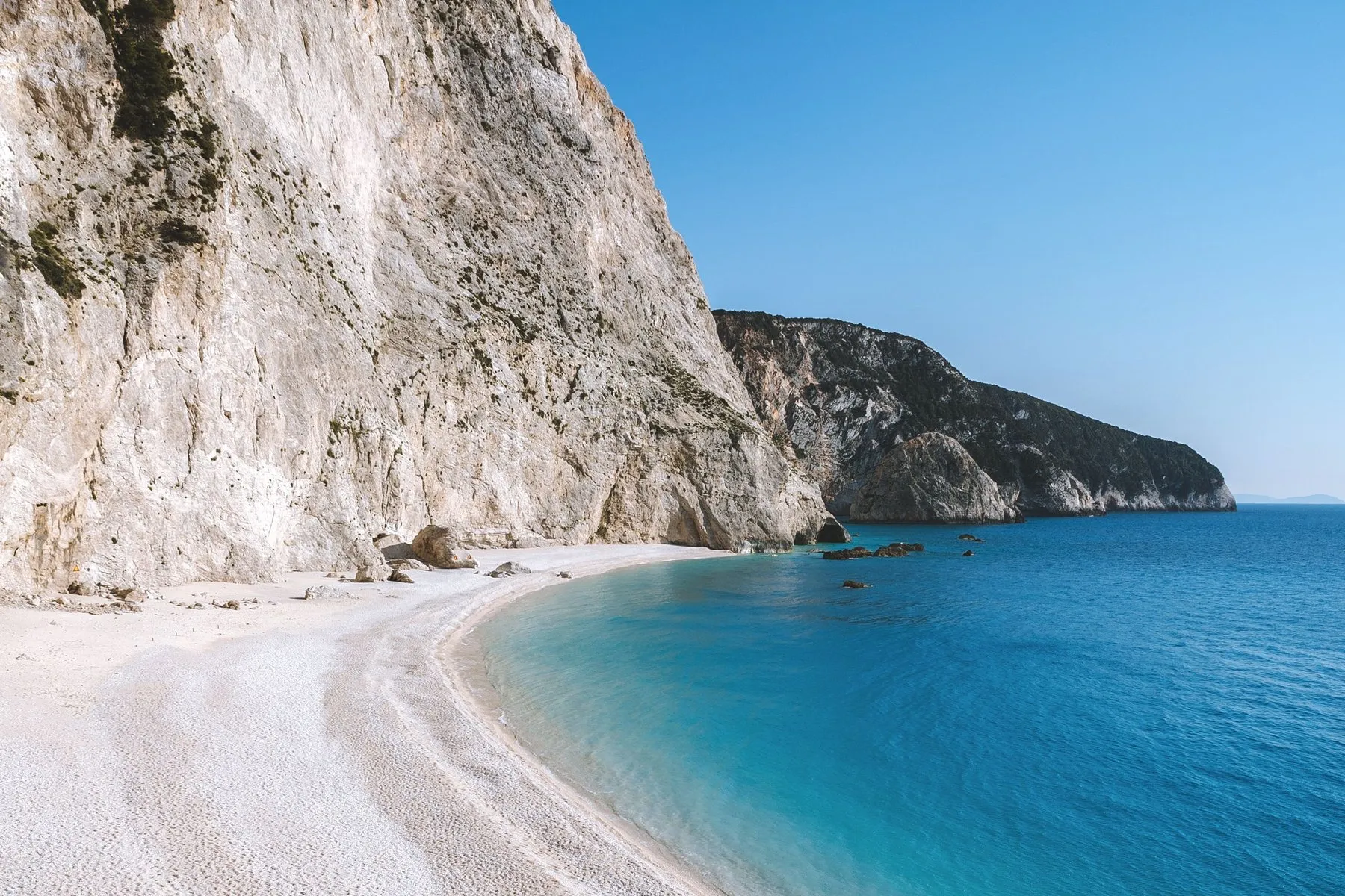 Porto Katsiki - Oasis Sailing Porto Katsiki from the water, white cliffs above a curving beach and turquoise shallows
