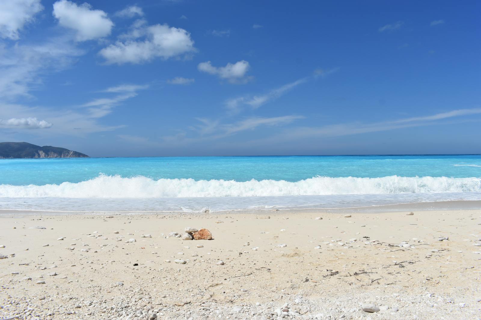 Serene beach view at Myrtos Beach, Kefalonia, Greece with clear blue skies and turquoise waters.